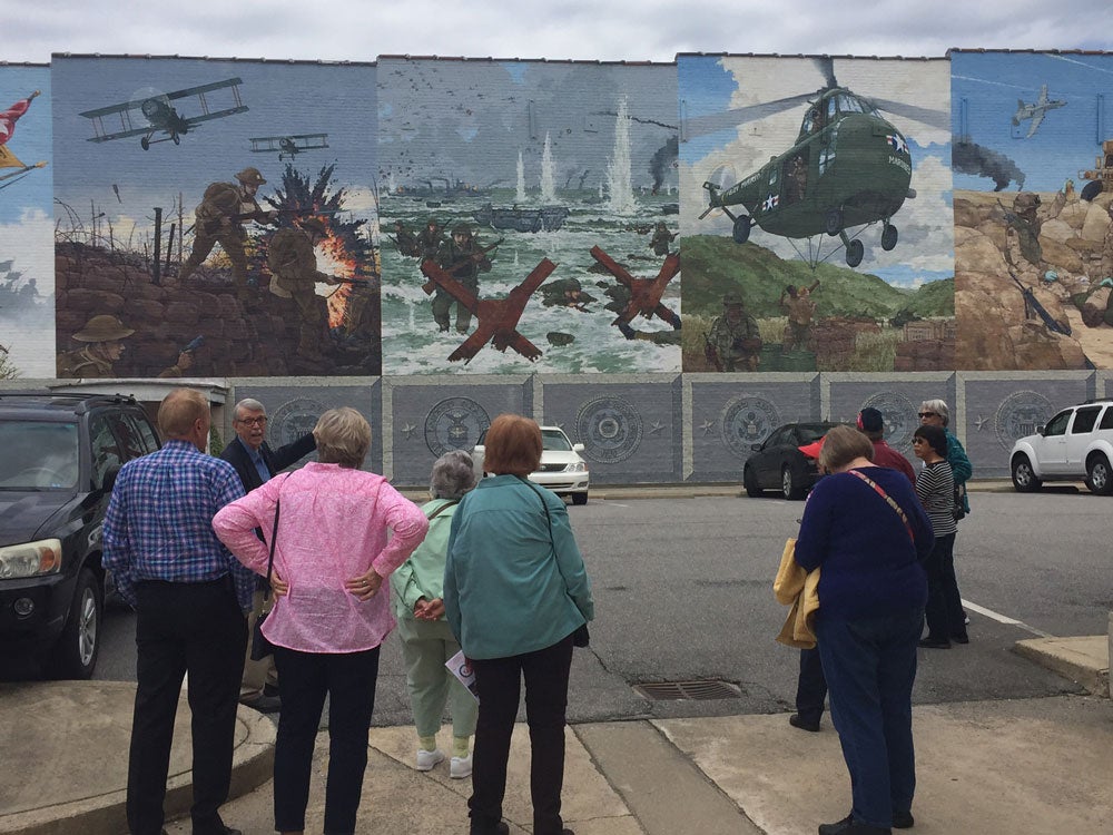 Image of trip participants viewing the decorative wall murals at the Veteran's museum in Tarboro, NC